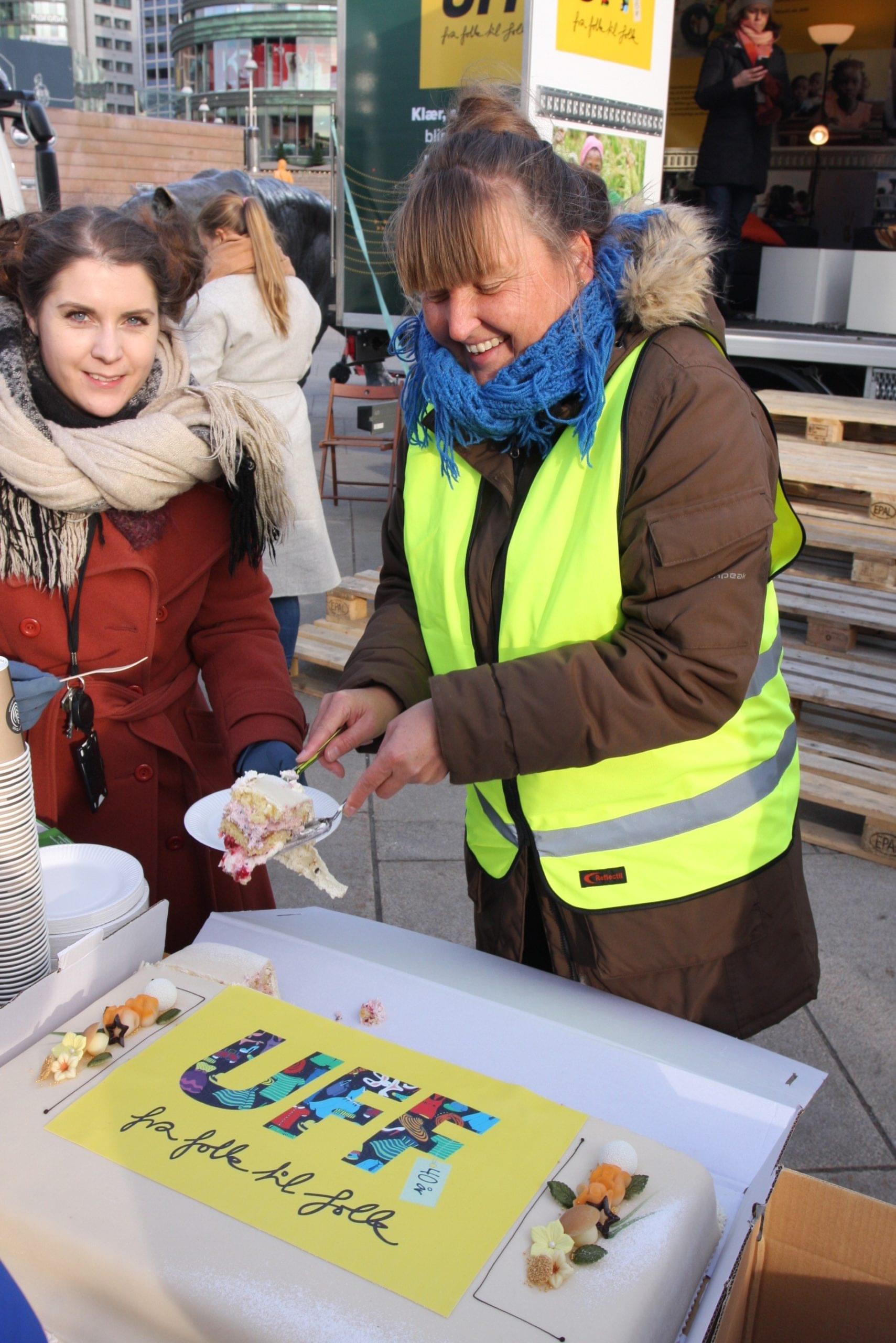 Sara Bjareng, avdelingsleder i UFF Second Hand (t.v.) og informasjonsansvarlig Rosa Fridh i UFF Norge t.h. og serverer jubileumskake til de frammøtte etter seremonien på Jernbanetorget.